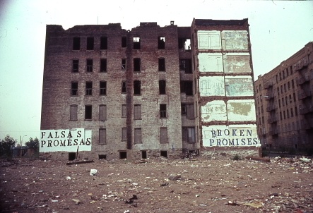 A run down building in the Bronx, whose wall says "Broken Promises" in both English and Spanish